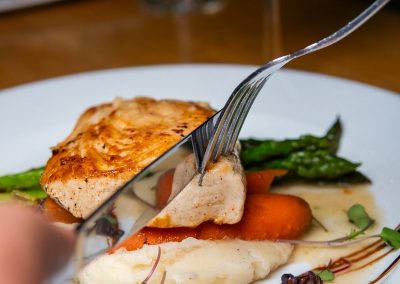 angle of knife cutting salmon and carrots with asparagus